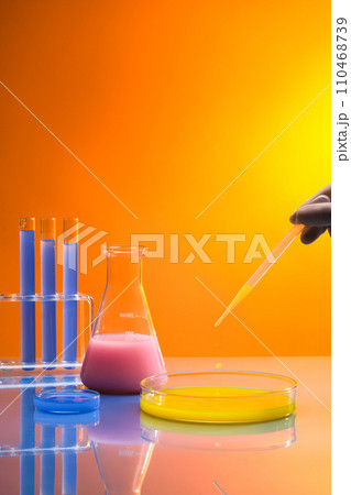 Over the gradient background, hand model with white glove is dripping yellow chemical into a large petri dish. Chemistry lab laboratory technical equipment with many glassware bottle Over the gradient background, hand model with white glove is dripping yellow chemical into a large petri dish. Chemistry lab laboratory technical equipment with many glassware bottle 110468739