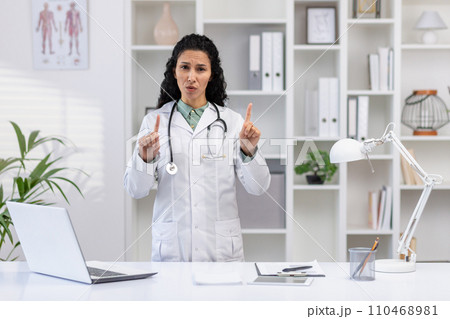 Portrait of female doctor inside clinic office, woman unhappy and upset looking at camera pointing fingers gesture no, working at desk with laptop. Portrait of female doctor inside clinic office, woman unhappy and upset looking at camera pointing fingers gesture no, working at desk with laptop. 110468981