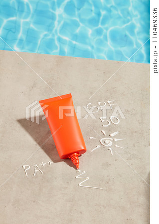 Concept of protecting the delicate skin of the face and spa with a red tube of sunscreen displayed near the pool. SPF 50 and PA++ texture. Container packaging of skin care branding Concept of protecting the delicate skin of the face and spa with a red tube of sunscreen displayed near the pool. SPF 50 and PA++ texture. Container packaging of skin care branding 110469336