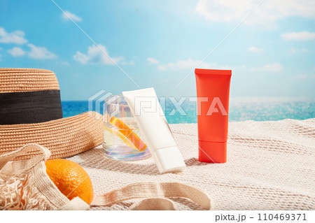 Sunscreen tubes in different colors displayed on the scarf with a water cup, beach hat and a mesh bag of oranges. Cosmetic concept with sun protection and regenerating products for skin Sunscreen tubes in different colors displayed on the scarf with a water cup, beach hat and a mesh bag of oranges. Cosmetic concept with sun protection and regenerating products for skin 110469371