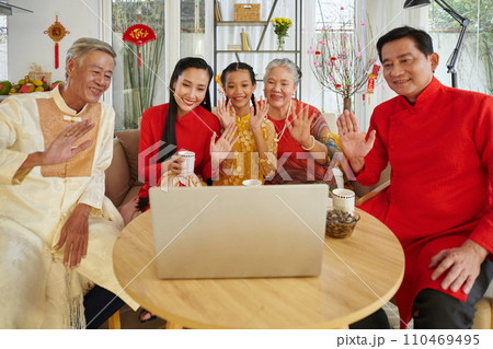 Vietnamese family in traditional costumers video calling relatives to wish happy Lunar New Year Vietnamese family in traditional costumers video calling relatives to wish happy Lunar New Year 110469495