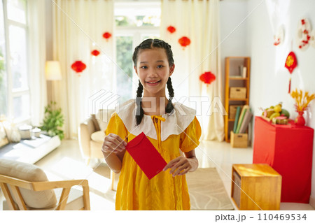 Smiling girl holding red envelope with money as traditional Tet present from family members 110469534