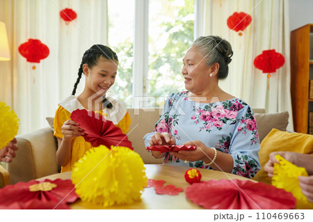Grandmother teaching granddaughter how to make paper garland for spring festival Grandmother teaching granddaughter how to make paper garland for spring festival 110469663