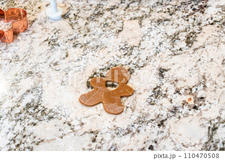 In a contemporary white kitchen, gingerbread cookie dough is skillfully rolled out, setting the stage for a delightful holiday treat. 110470508