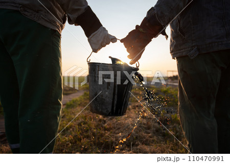 Workers carry a bucket of spilled extracted oil. Discover oil fields. Black gold. Workers carry a bucket of spilled extracted oil. Discover oil fields. Black gold. 110470991