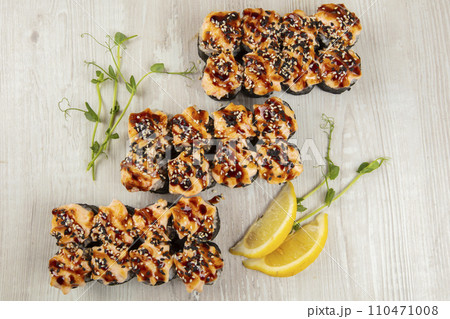 Set of baked sushi rolls sprinkled with sesame seeds on a white wooden background. Set of baked sushi rolls sprinkled with sesame seeds on a white wooden background. 110471008
