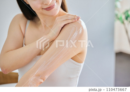 二の腕にクリームを塗ってボディケアする30代女性 二の腕にクリームを塗ってボディケアする30代女性 110473667