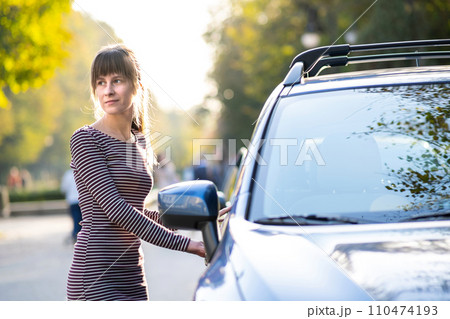 Young female driver resting near her car enjoying warm summer day. Travel and getaway concept. 110474193