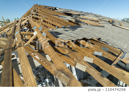 Wind damaged house roof with missing asphalt shingles after hurricane Ian in Florida. Repair of home rooftop concept 110474206