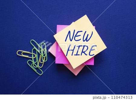 New Hire symbol. Orange steaky note with concept words New Hire. Beautiful deep blue background. Business and New Hire concept. Copy space. 110474313