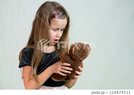 Pretty child girl playing with her teddy bear toy. Pretty child girl playing with her teddy bear toy. 110474511