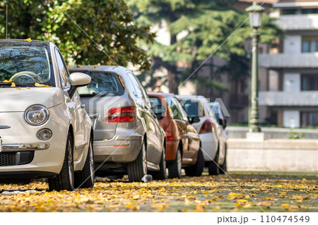 Modern cars parked on city street side in residential discrict. Shiny vehicles parked by the curb. Urban transportation infrastructure concept. 110474549