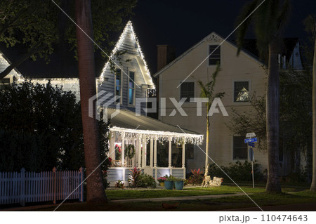 House front yard with big porch brightly illuminated with Christmas decorations. Outside decor of Florida family home for winter holidays 110474643