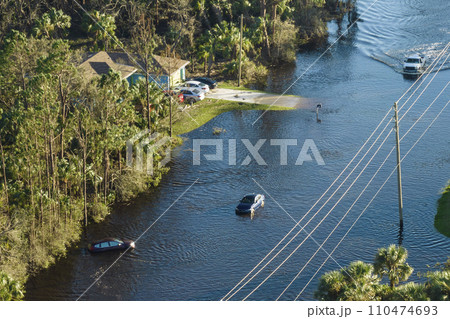 Flooded road in Florida after heavy hurricane rainfall. Aerial view of evacuating cars and surrounded with water houses in suburban residential area Flooded road in Florida after heavy hurricane rainfall. Aerial view of evacuating cars and surrounded with water houses in suburban residential area 110474693