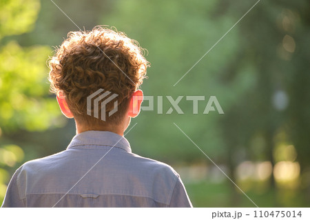 Back view of young teenage boy with curly blond hair 110475014