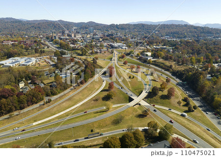 American freeway intersection in Asheville, North Carolina with fast driving cars and trucks in autumnal season. View from above of USA transportation infrastructure American freeway intersection in Asheville, North Carolina with fast driving cars and trucks in autumnal season. View from above of USA transportation infrastructure 110475021