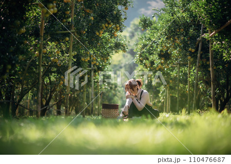 A happy woman farmer is resting in orchard or orange farm. 110476687