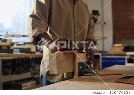 Close up of unrecognizable senior craftsman polishing wood building furniture in sunlit workshop 110476858