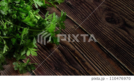 Green parsley leaves - used as herb in kitchen - on dark wooden board, wide banner Green parsley leaves - used as herb in kitchen - on dark wooden board, wide banner 110476970