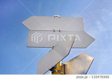 Empty metal tables shaped like arrows against blue sky - add your text 110476980