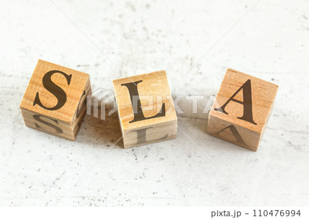 Three wooden cubes with letters SLA (stands for Service Level Agreement) on white board. 110476994