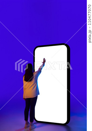 Woman confidently interacting with phone, showcasing classic touch gesture, with empty screen. Suitable for technology product advertisements. Woman confidently interacting with phone, showcasing classic touch gesture, with empty screen. Suitable for technology product advertisements. 110477070