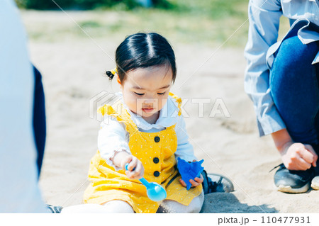 公園で砂遊びする親子 110477931