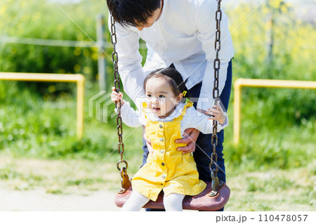 公園のブランコで遊ぶかわいい女の子とお父さん 公園のブランコで遊ぶかわいい女の子とお父さん 110478057
