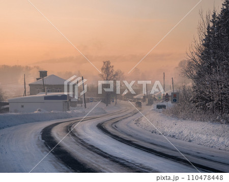 Frosty morning sunrise winter snow-covered highway through Cherdyn village 110478448