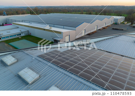 Aerial view of solar power plant with blue photovoltaic panels mounted on industrial building roof for producing green ecological electricity. Production of sustainable energy concept 110478593