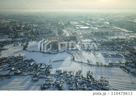 Aerial view of private homes with snow covered roofs in rural suburbs town area in cold winter Aerial view of private homes with snow covered roofs in rural suburbs town area in cold winter 110478613