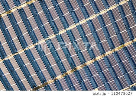 Aerial view of many photo voltaic solar panels mounted of industrial building roof. 110478627