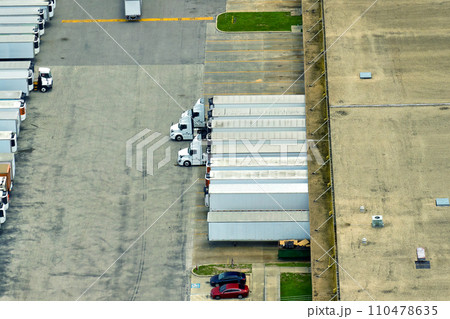 Aerial view of large commercial loading bay with many delivery trucks unloading and uploading retail goods for nationwide distribution. Global economy concept 110478635