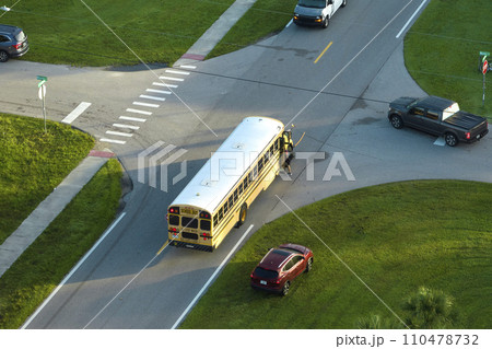 Aerial view of american yellow school bus picking up children at sidewalk bus stop for their lessongs in early morning. Public transportation in the USA 110478732