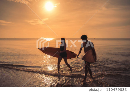 Asian couple holding surfboard on the beach at morning 110479028