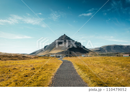 Stapafell volcanic mountain in Arnarstapi fishing village and pathway through golden meadow at Iceland 110479052