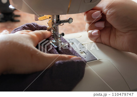Close-up of a woman's hands sewing on a sewing machine Close-up of a woman's hands sewing on a sewing machine 110479747