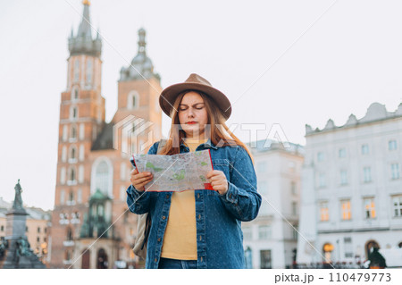Portrait beautiful woman with paper map on urban street. Young worried female traveler lost in the city using map. Vacation concept by exploring interesting places to travel. St. Marys Basilica 110479773