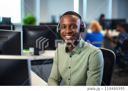 A smiling African-American man with headphones and a microphone in a call center A smiling African-American man with headphones and a microphone in a call center 110480395