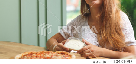 A girl dips a slice of pizza in sauce A girl dips a slice of pizza in sauce 110481092