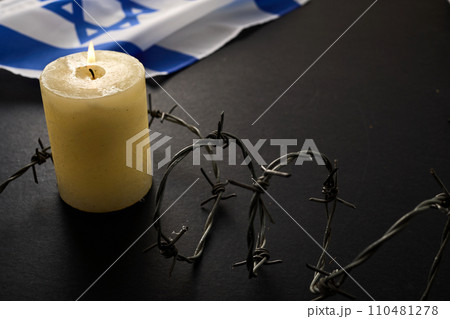 Flag of Israel, barbed wire and burning candle on black background. Holocaust memory day Flag of Israel, barbed wire and burning candle on black background. Holocaust memory day 110481278