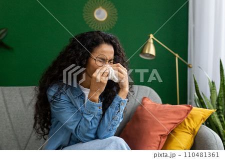 Lonely sad woman crying sitting at home on sofa in living room of house, Hispanic woman in distress and depression hopelessness. Lonely sad woman crying sitting at home on sofa in living room of house, Hispanic woman in distress and depression hopelessness. 110481361