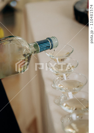 Waiter pouring martini or champagne in crystal glasses on table party at wedding reception 110481574