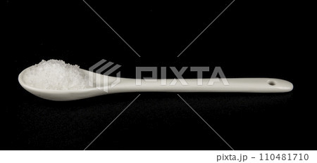 A spoonful of white salt on a black background. Sea food salt. 110481710