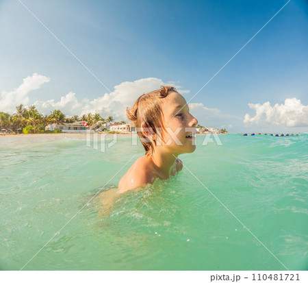 Joyful boy plays in the sea, creating playful splashes and enjoying the waves Joyful boy plays in the sea, creating playful splashes and enjoying the waves 110481721