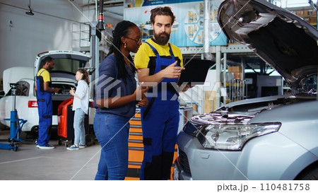 Mechanic in car service picks torque wrench from work station bench, using it to tighten bolts after replacing engine. Auto repair shop employee uses professional tools to fix client automobile 110481758