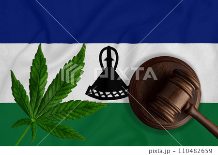 Justice wooden gavel with cannabis leaf on the Flag of Lesotho. Illegal growth of cannabis plant and drugs spreading Justice wooden gavel with cannabis leaf on the Flag of Lesotho. Illegal growth of cannabis plant and drugs spreading 110482659