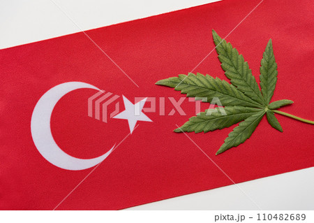Flag of Turkey close up and fresh cannabis leaf. Illegal cultivation and distribution. Medical use 110482689