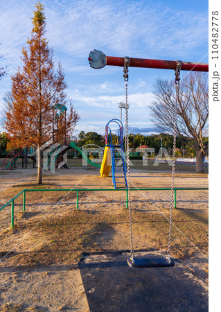 秋晴れ夕日光芒を浴びている公園風景(ブランコ) (益城町総合運動公園) 秋晴れ夕日光芒を浴びている公園風景(ブランコ) (益城町総合運動公園) 110482778