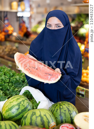 Young Muslim woman in niqab choosing watermelon in store Young Muslim woman in niqab choosing watermelon in store 110483227